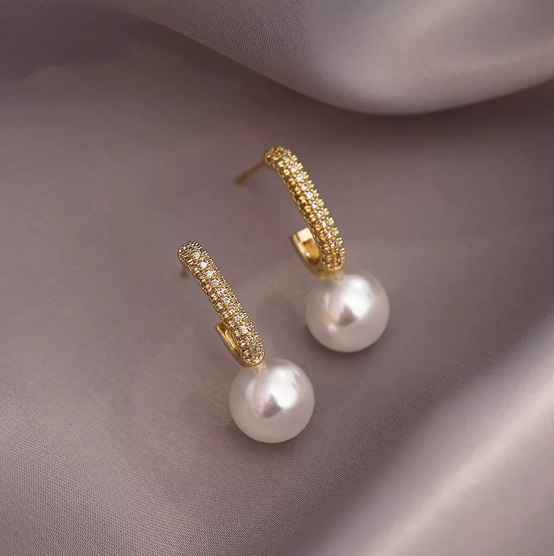 Pendientes elegantes de perlas doradas y luminosas